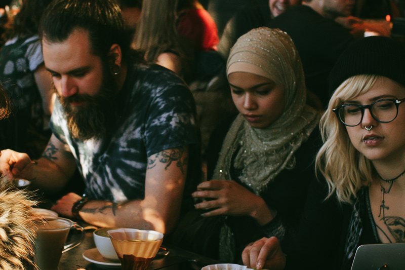 Three patrons gathered at a communal table over coffee at Cafe Socialist
